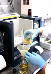 A lady technician testing oil with an industrial oil tester